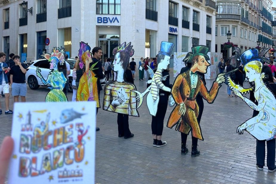 Participantes con figuras ilustradas de gran tamaño durante una actividad cultural de La Noche en Blanco 2025 en Málaga